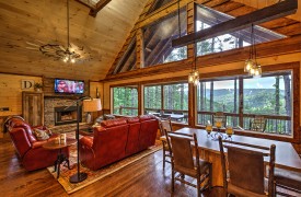 Cozy Conversational Living w/ Wood-burning Fireplace Above the Timberline | Cabin Rentals of Georgia | Luxury Living Area and Dining area with wall of windows looking at North GA Mountain views in daytime
