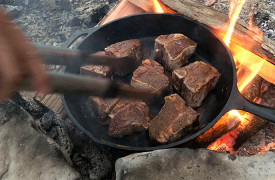 Cherokee Sunrise on Noontootla Creek | Cabin Rentals of Georgia | cooking lamb in iron skillet over Fire Pit