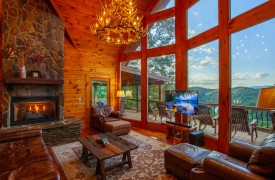 Riverview Lodge | Cabin Rentals of Georgia | Spacious Living Area with two story open ceiling, antler chandelier, leather furnishings, stone gas log fireplace