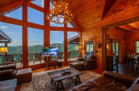 Riverview Lodge | Cabin Rentals of Georgia | Spacious Living Area with two story open ceiling, antler chandelier, leather furnishings, stone gas log fireplace