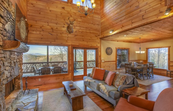 High Hopes | Cabin Rentals of Georgia | Living Room cozy furnishings in front of stone fireplace and picture windows showcasing mountain views